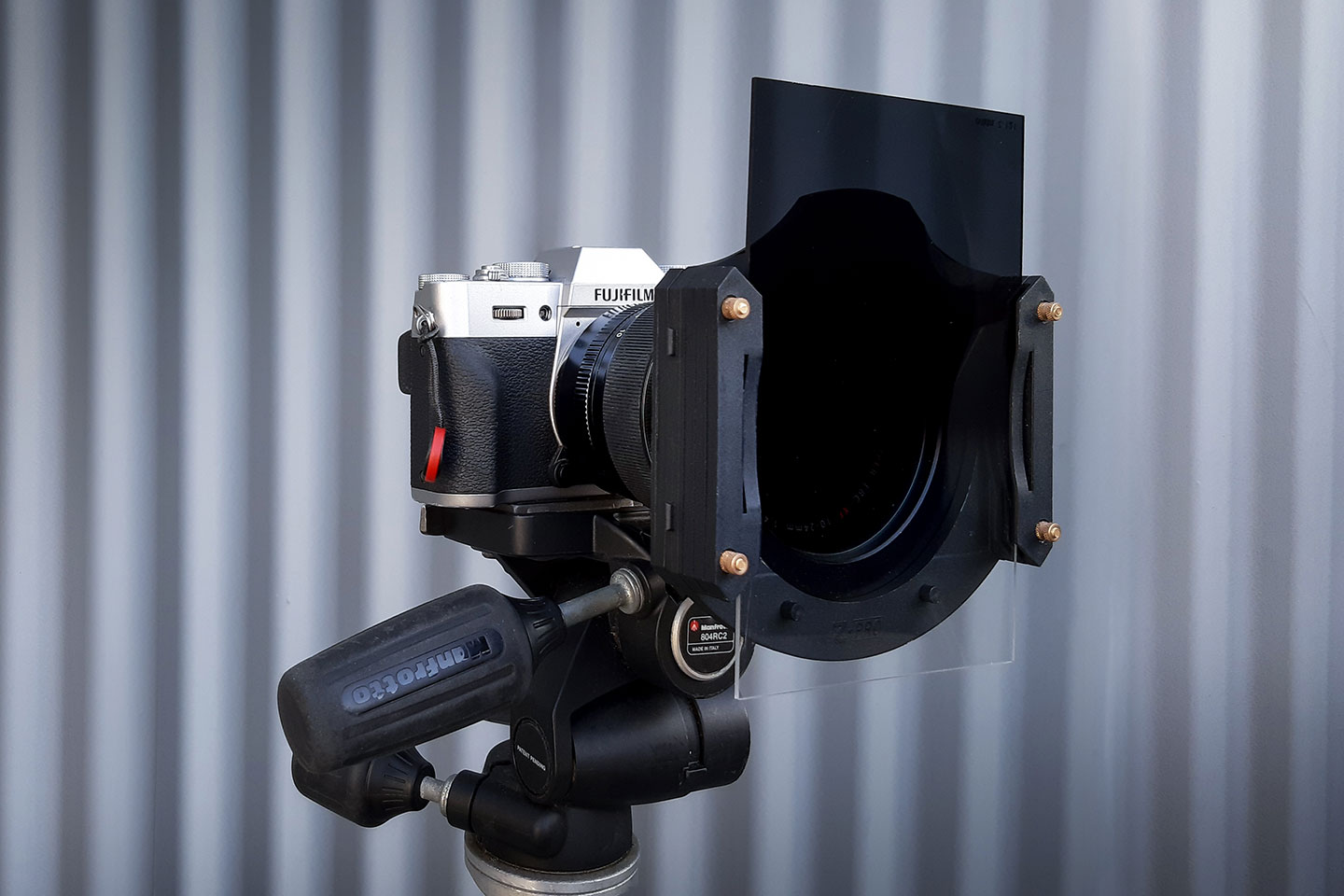 A mirrorless camera mounted on a tripod with a graduated neutral density filter attached to the front. A great addition to any photography equipment list.