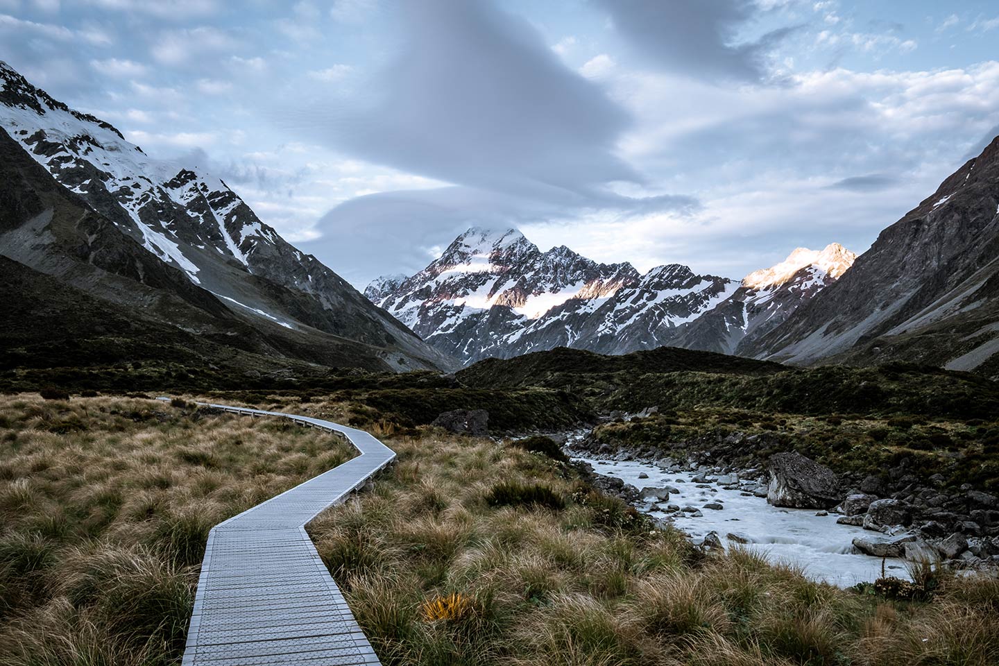 A wooden path leads towards Aoraki/Mount Cook with moody clouds above. This image has been edited using the Sharp Desaturated Vibes preset which is included as part of the moody Lightroom presets package.