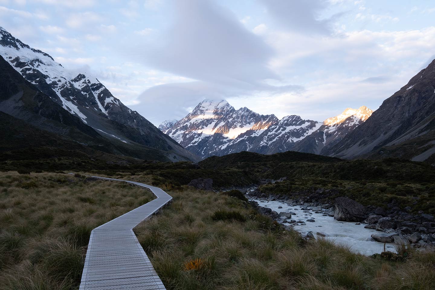 A wooden path leads towards Aoraki/Mount Cook with moody clouds above. This is the RAW unedited image without a preset applied.