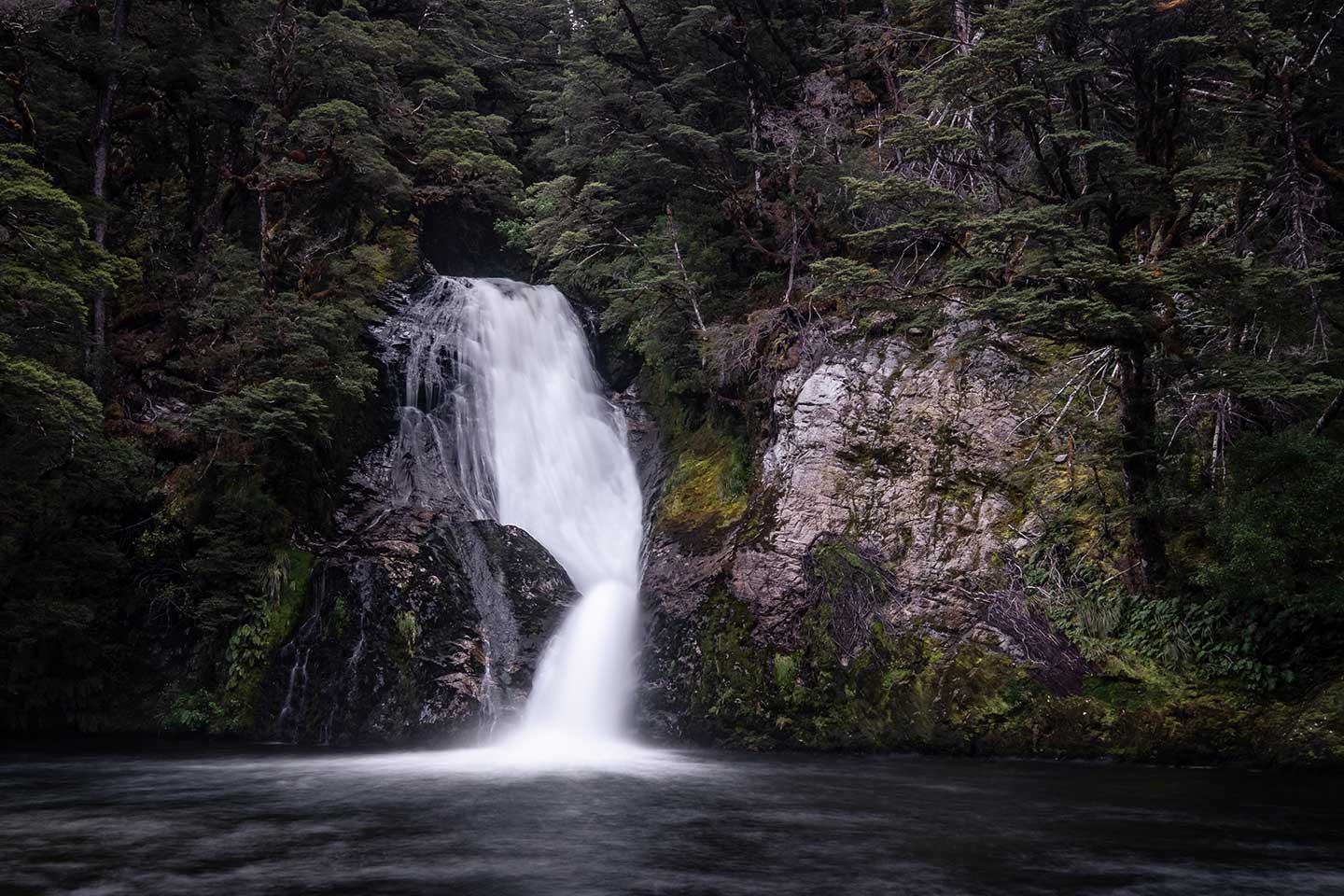 White rapid waters flow down the Iris Burn waterfall to the still water below